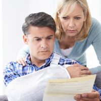A man and a woman couple with a concerned look, analyzing bills and paperwork